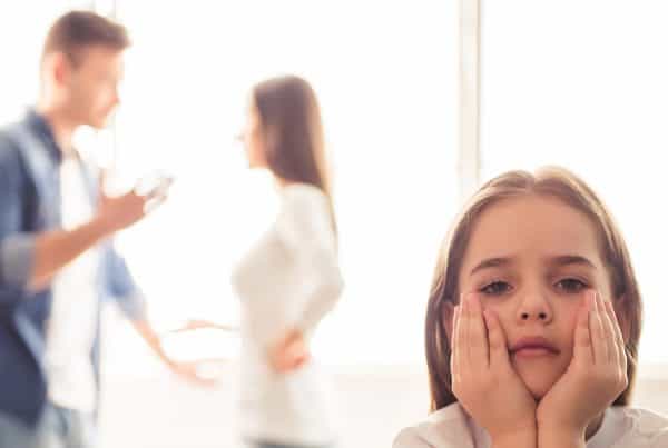 Girl looks sad as parents argue in the background